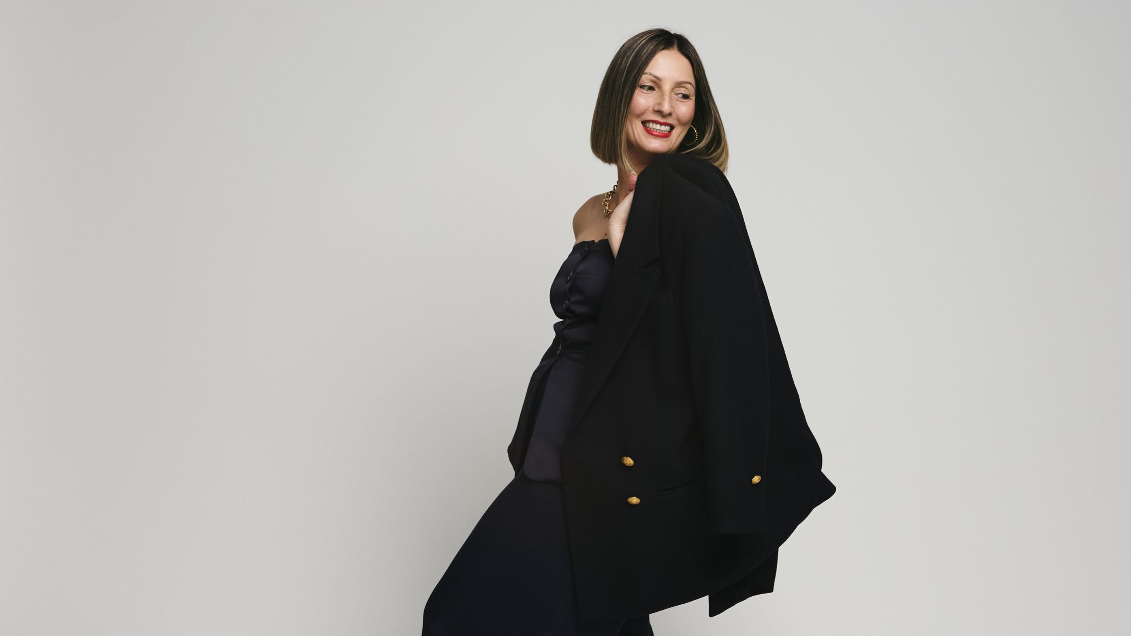 Roberta Lee, London's Style & Identity Expert wears a Monocromatic Navy Blue Outfit, Smiles and Looks over her shoulder. Combining a modern blue 2-piece, with a vintage blazer and vintage jewellery + red lips. Her look is understated, calm and confident.